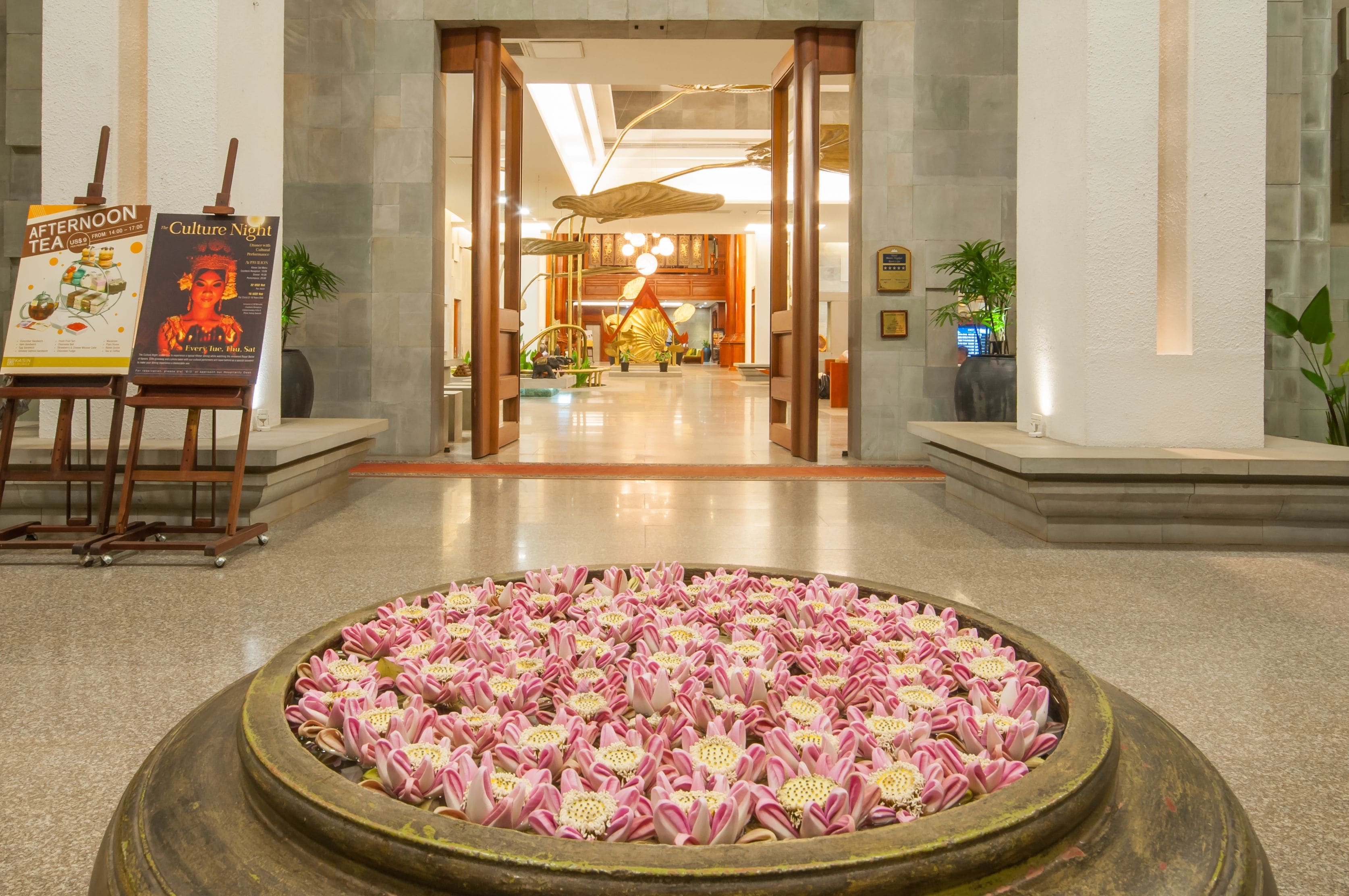 A lobby with a central fountain, wooden columns, and a reception desk.