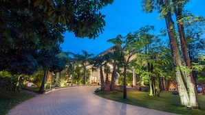 A paved pathway leading to a building with a curved entrance, surrounded by trees and well-maintained grass. - Borei Angkor Resort & Spa (Siem Reap)