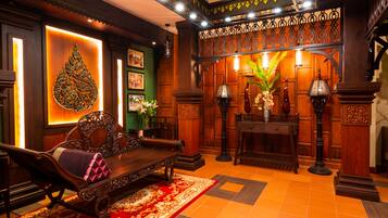 A traditional room with a wooden sofa, ornate lamp, and a decorative wall with a green panel.