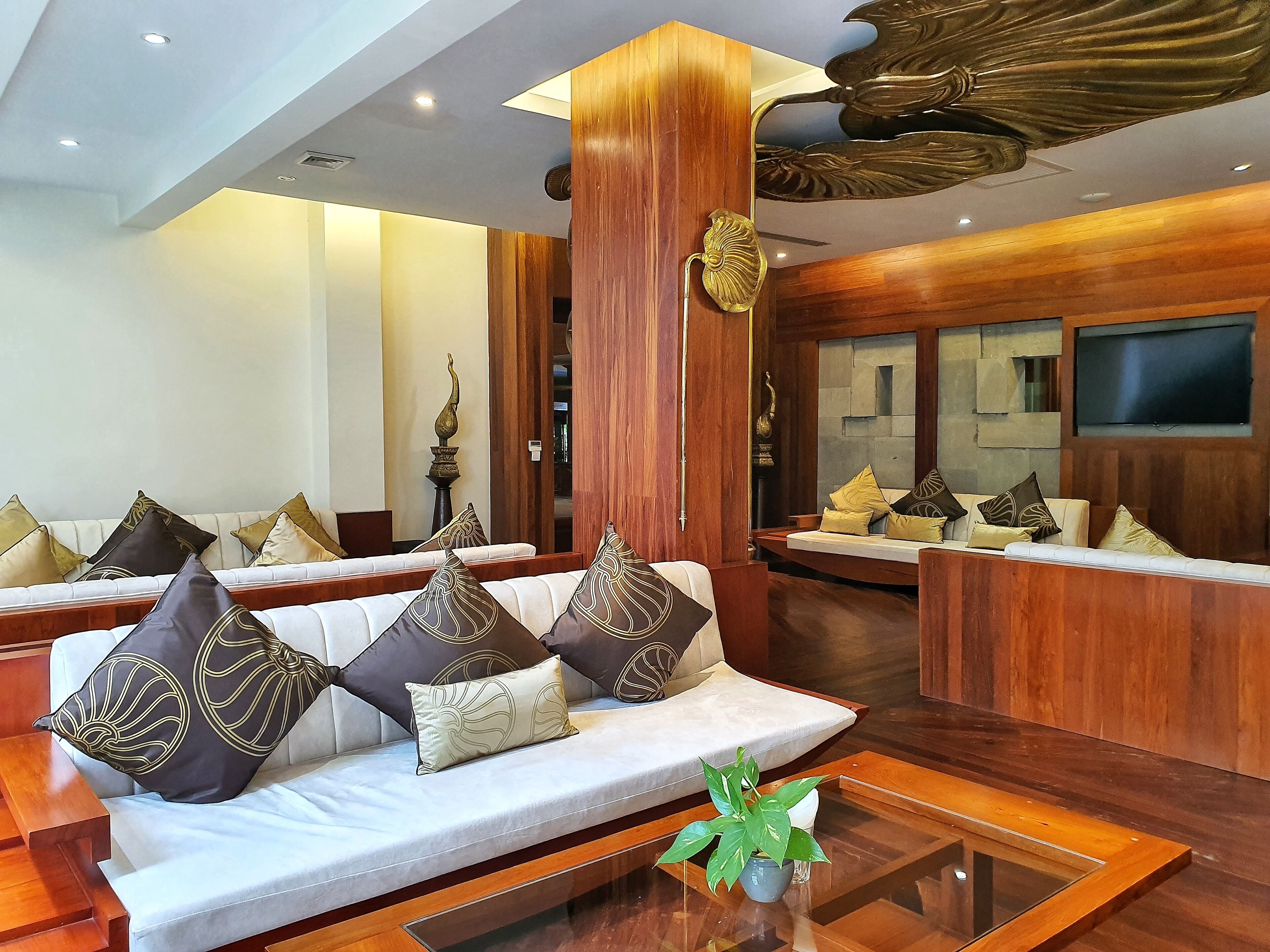 A hotel lobby with a reception desk, sofas with patterned cushions, and decorative vases.