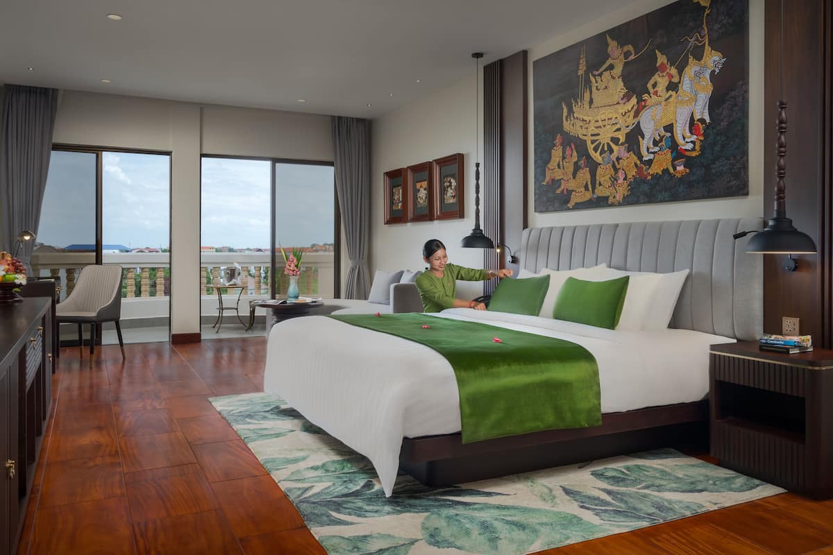 Une chambre d’hôtel avec un grand lit, un balcon avec vue et un tableau au mur.