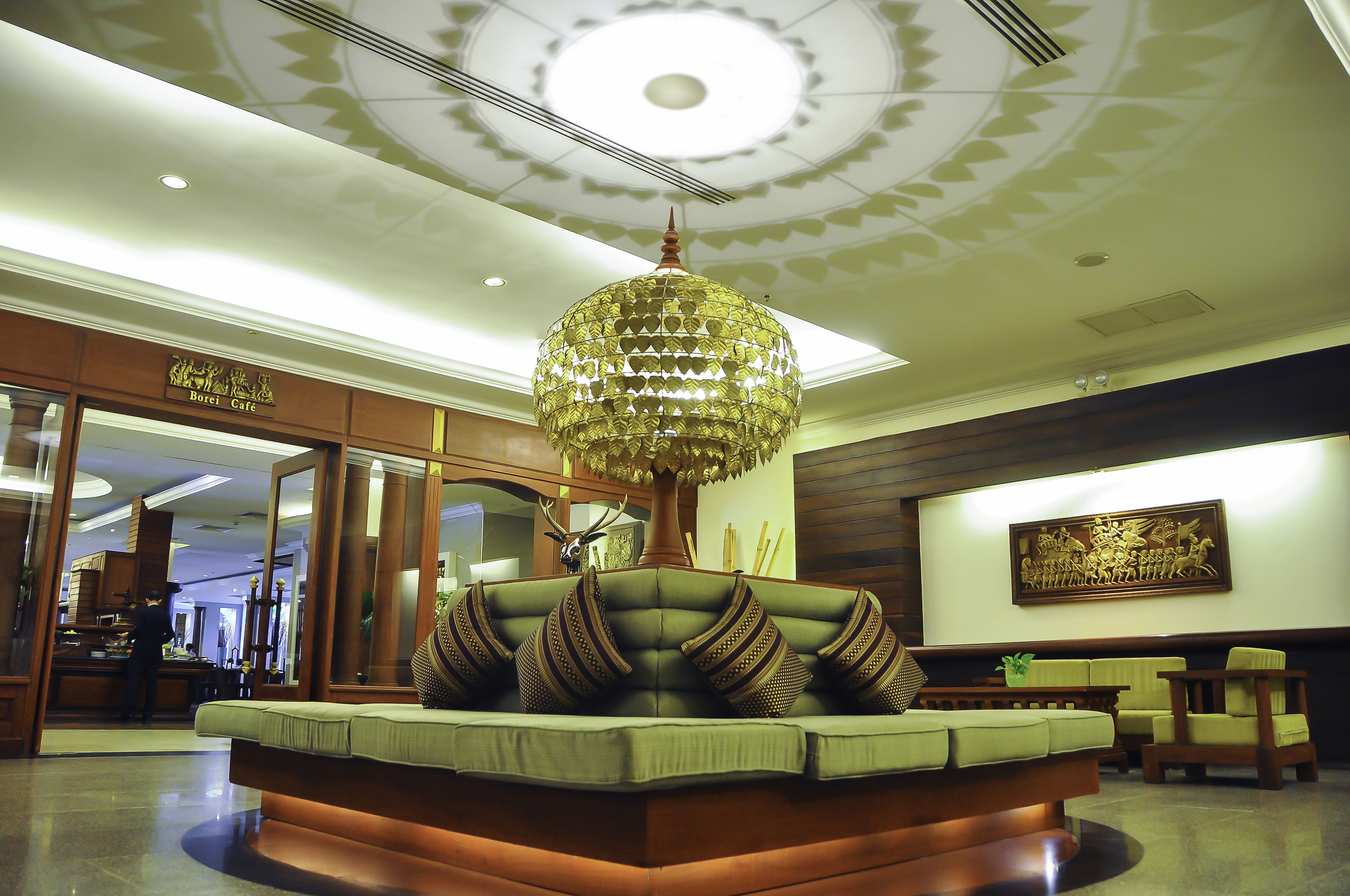 A lobby with a green sofa, a large chandelier, and a wooden reception desk.