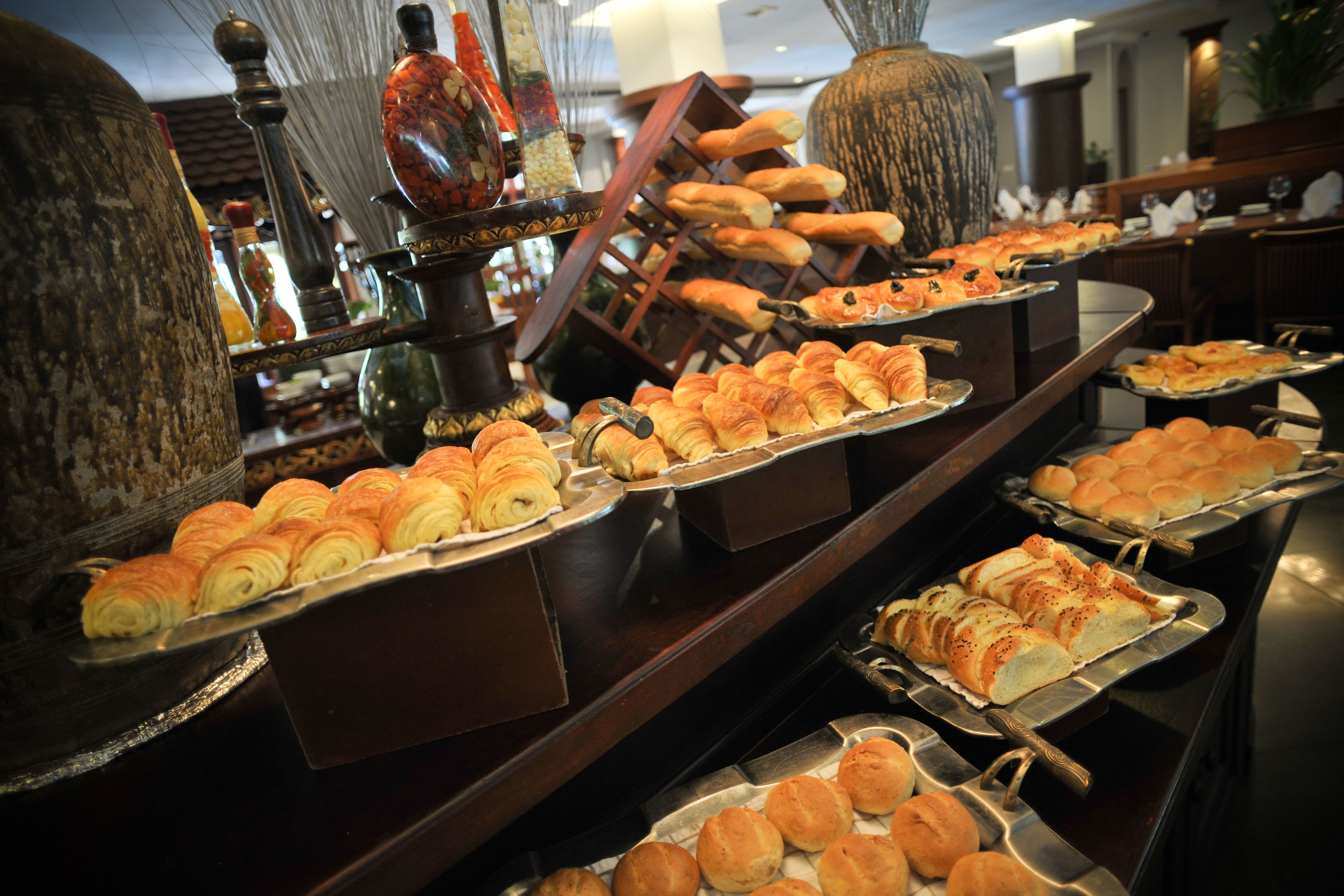 A buffet with various baked goods including croissants and rolls.