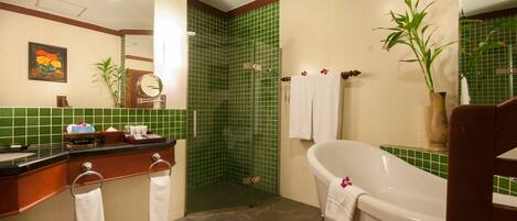 A bathroom with a bathtub, a shower, and a vanity with a mirror.