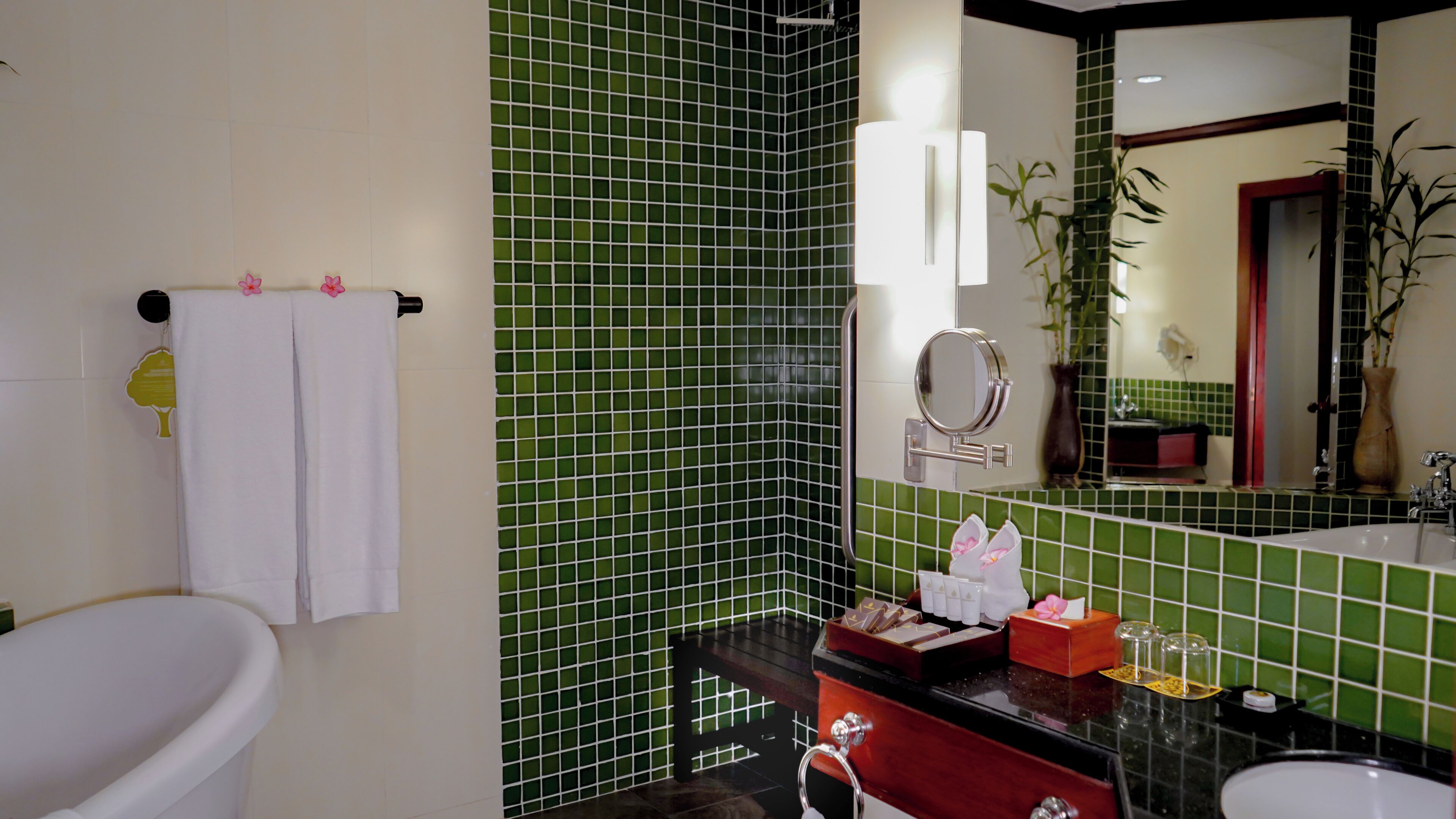 Un baño con una bañera blanca, un lavabo con artículos de aseo y un espejo.