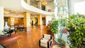 A spacious lobby with a grand piano, comfortable seating, a reception desk, and a staircase leading to an upper level. - Seagull Hotel (Quy Nhon Nam)