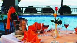 A table set for dining with a view of the pool and ocean. - Seagull Hotel (Quy Nhon Nam)