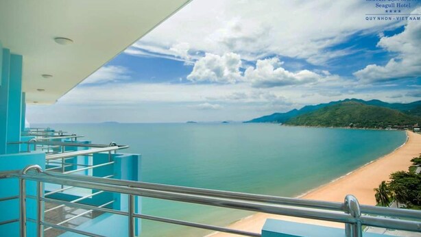 A hotel balcony with a view of a beach and mountains. - Seagull Hotel (Quy Nhon Nam)