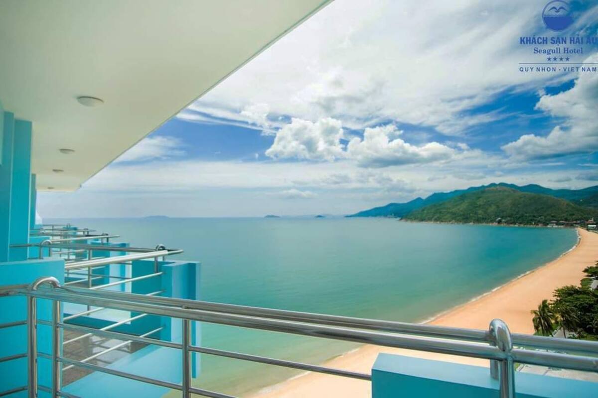A hotel balcony with a view of a beach and mountains.