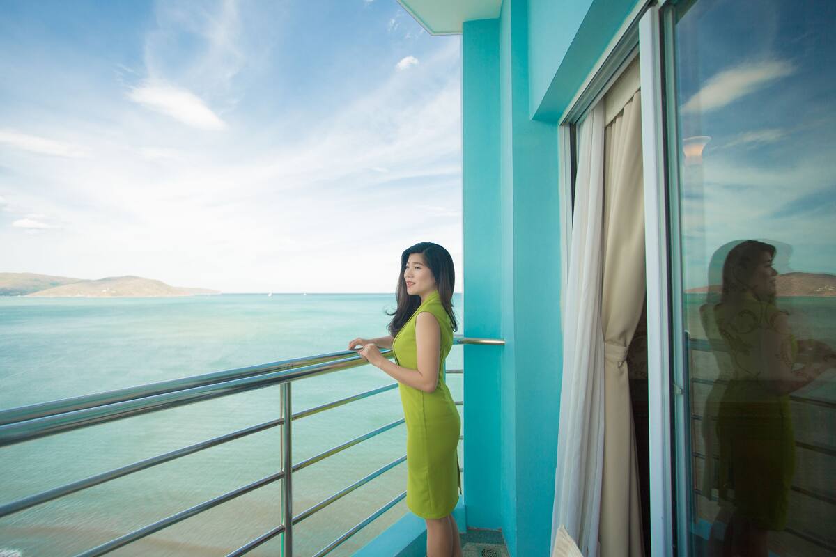 A balcony with a view of the sea and distant hills.