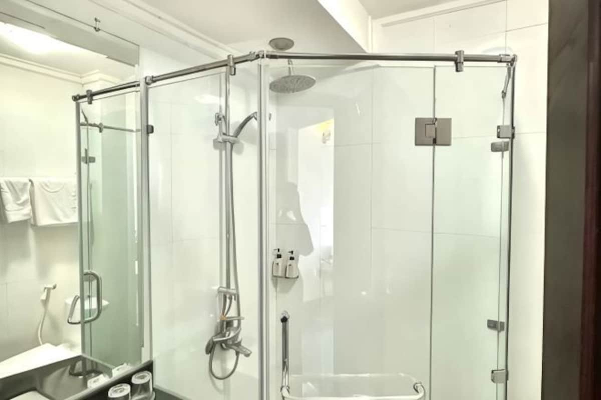 Ducha envuelta en vidrio con ducha de mano y grifo de mano.