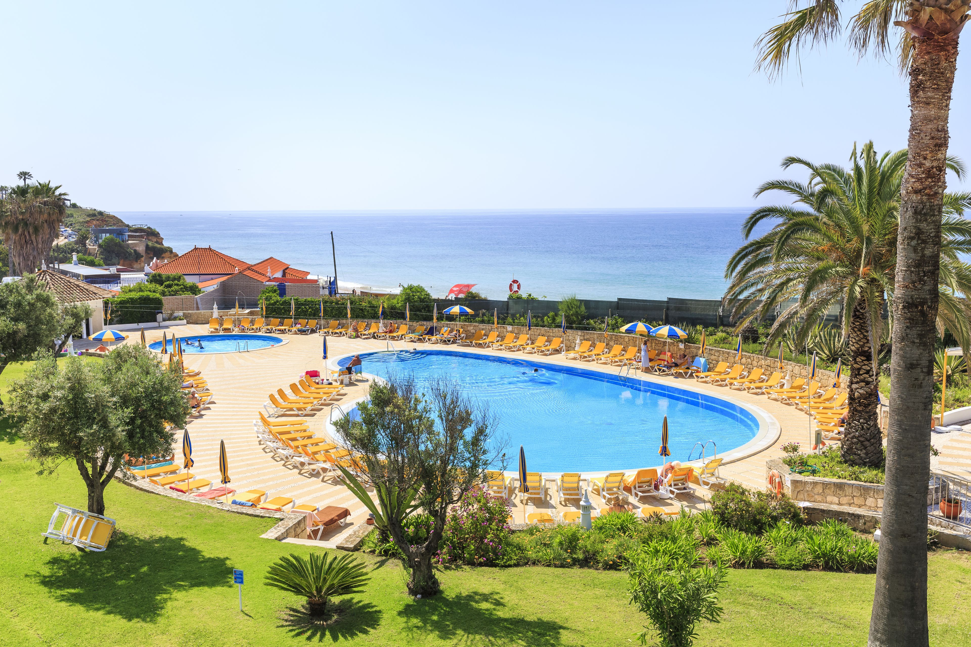 A resort with a large pool, sun loungers, and a view of the ocean.
