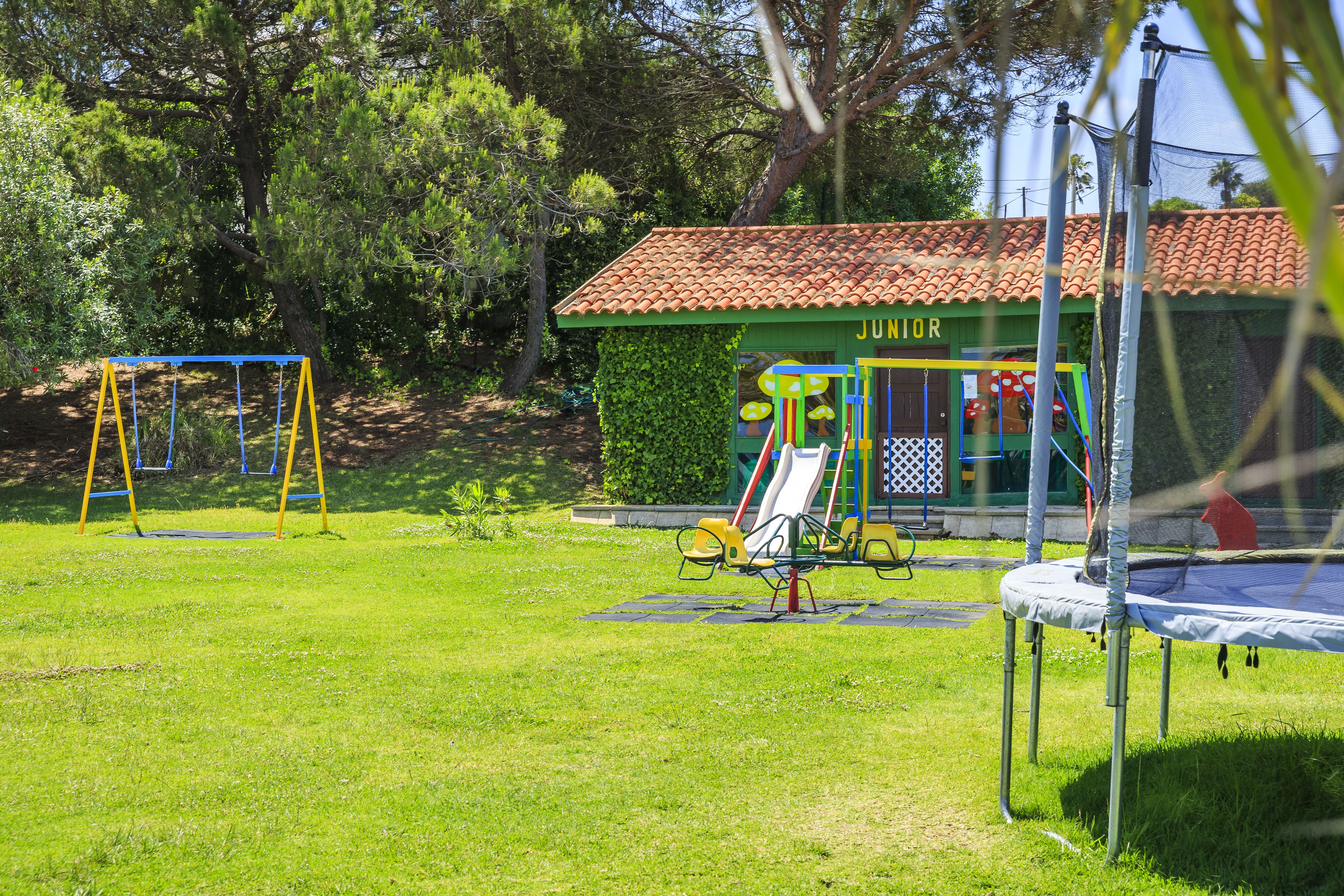 A playground with swings, a slide, and a trampoline.