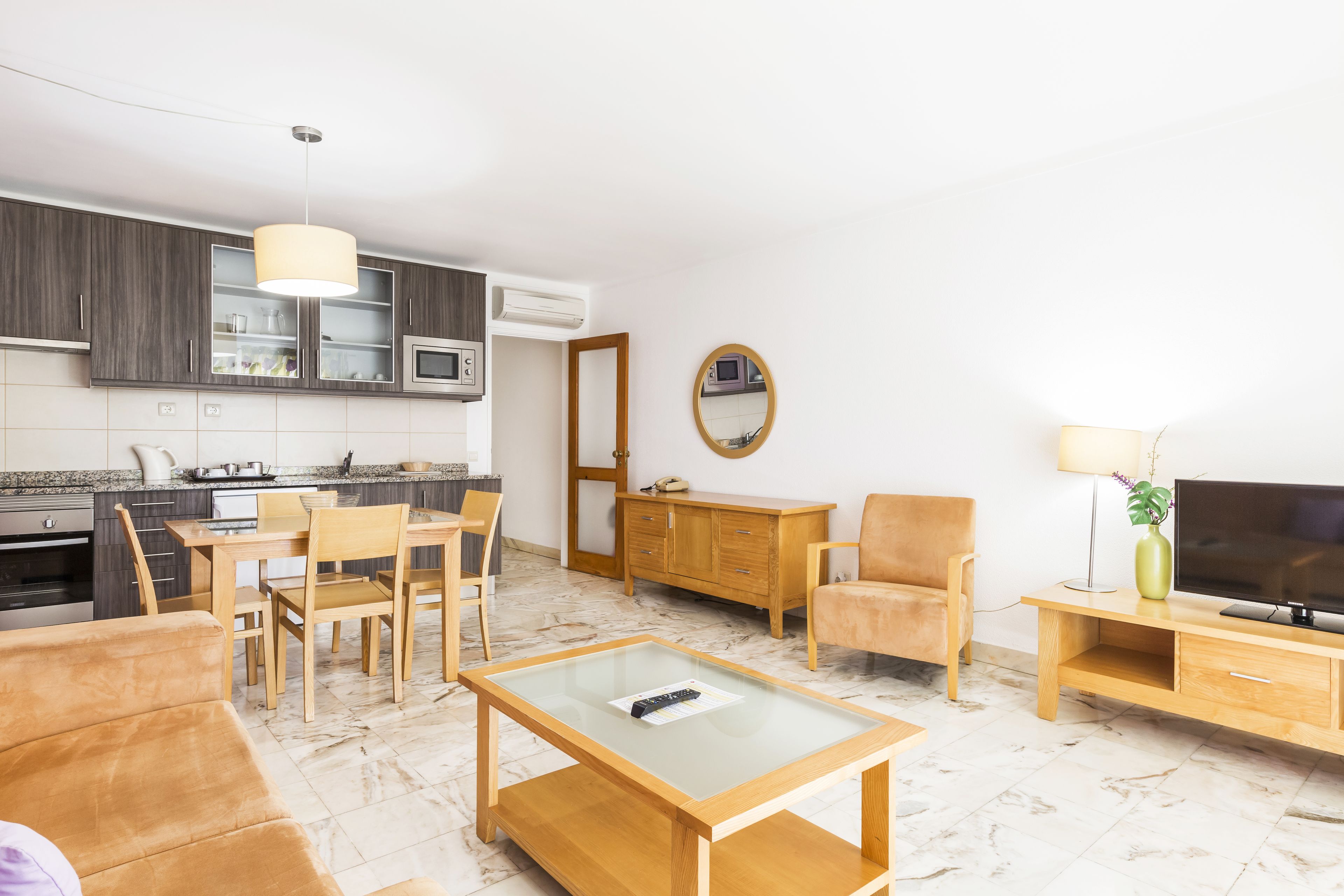 Un soggiorno moderno con divano, tavolino, televisore e zona pranzo con sedie e tavolo.