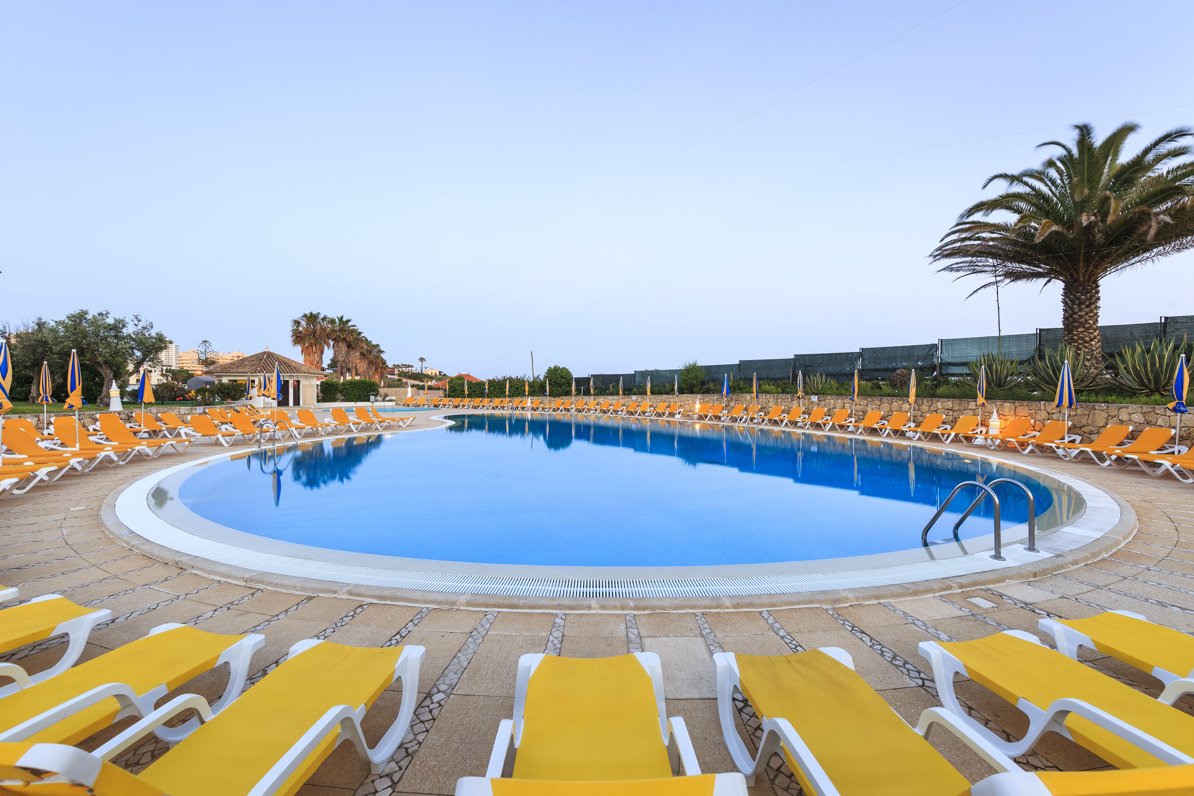 A swimming pool with yellow and white lounge chairs arranged around it.