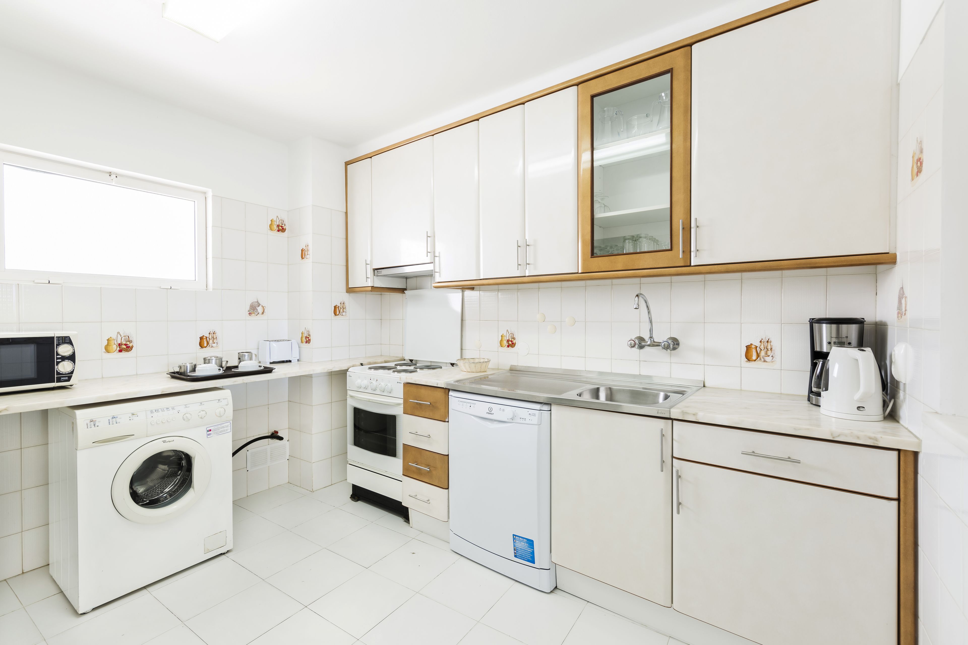 A compact kitchen with white cabinets, a microwave, a stove, a dishwasher, and a sink.