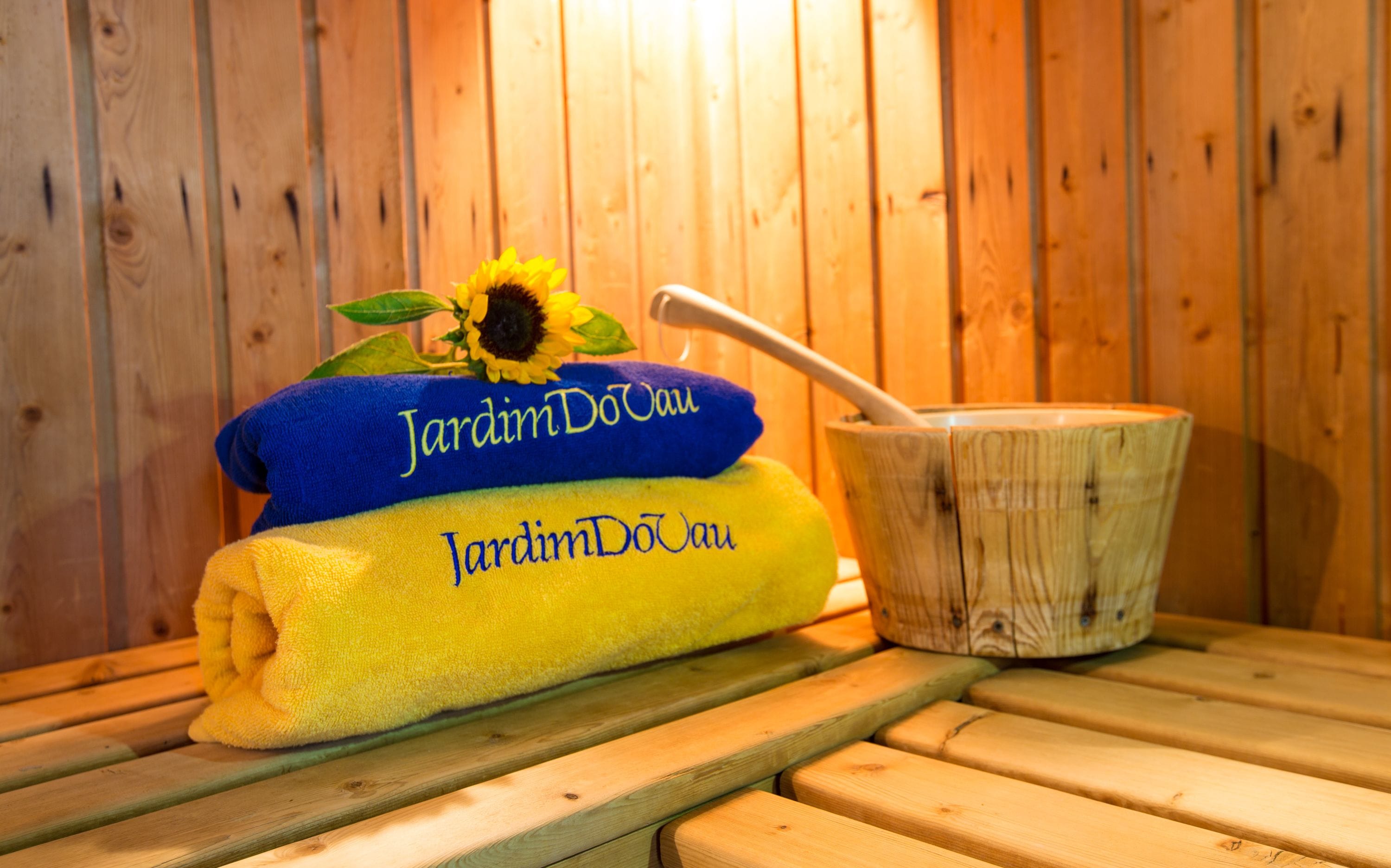 A wooden sauna bench with a towel and a wooden bucket.