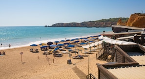 A beach with sun loungers and umbrellas, a wooden deck, and a restaurant with a bar. - Jardim do Vau (Portimão)