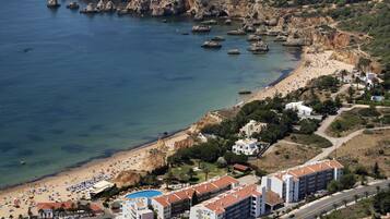 A coastal hotel with a swimming pool, beach access, and a view of the rocky coastline.