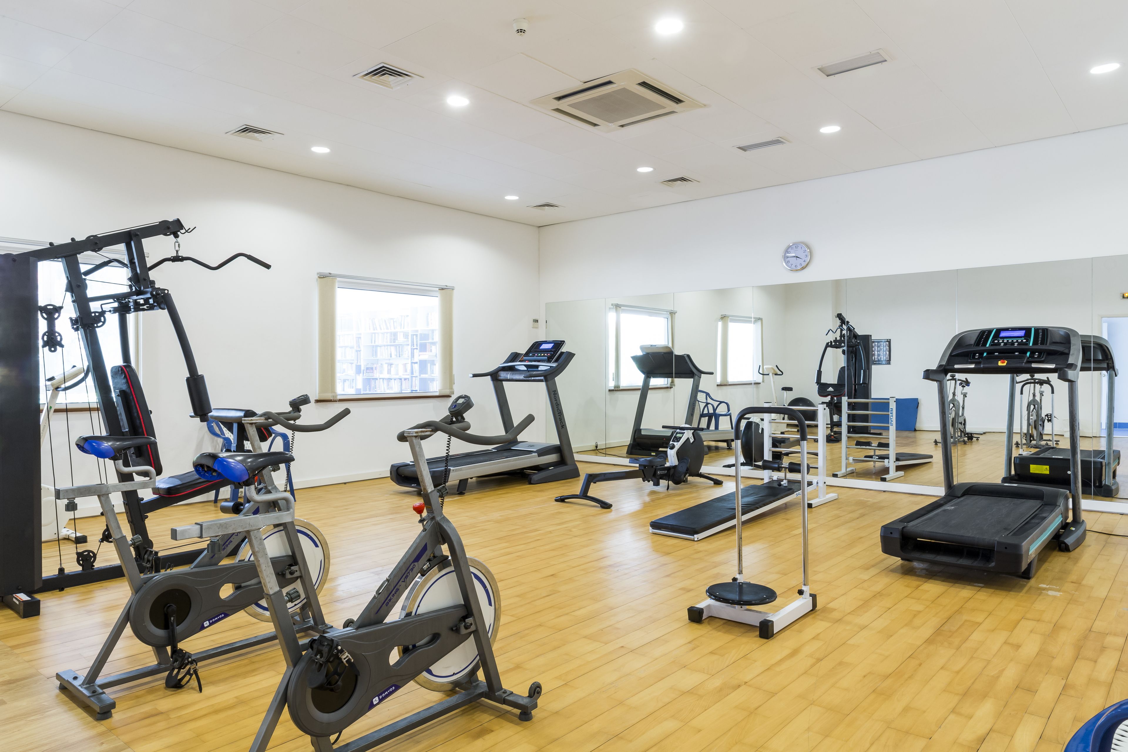 Ett rymligt gym med olika typer av träningsutrustning, inklusive löpband, motionscyklar och styrketräningsmaskiner.