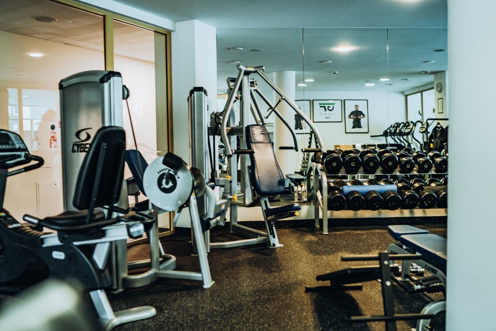 A gym with cardio machines, weightlifting equipment, and a rack of dumbbells.