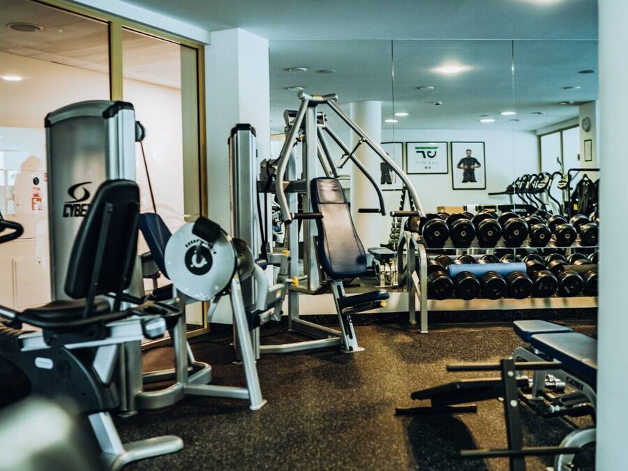 A gym with cardio machines, weightlifting equipment, and a rack of dumbbells.
