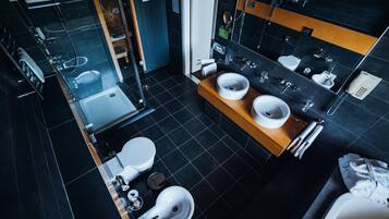 A modern bathroom with two sinks, a toilet, and a shower.