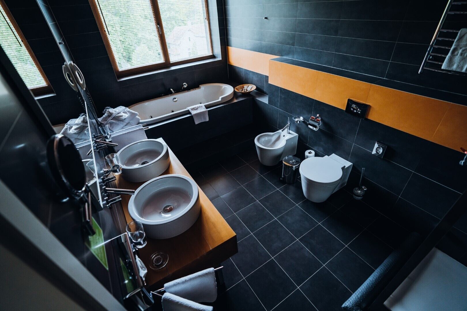 Une salle de bain moderne avec une grande baignoire, deux lavabos, un bidet et des toilettes.
