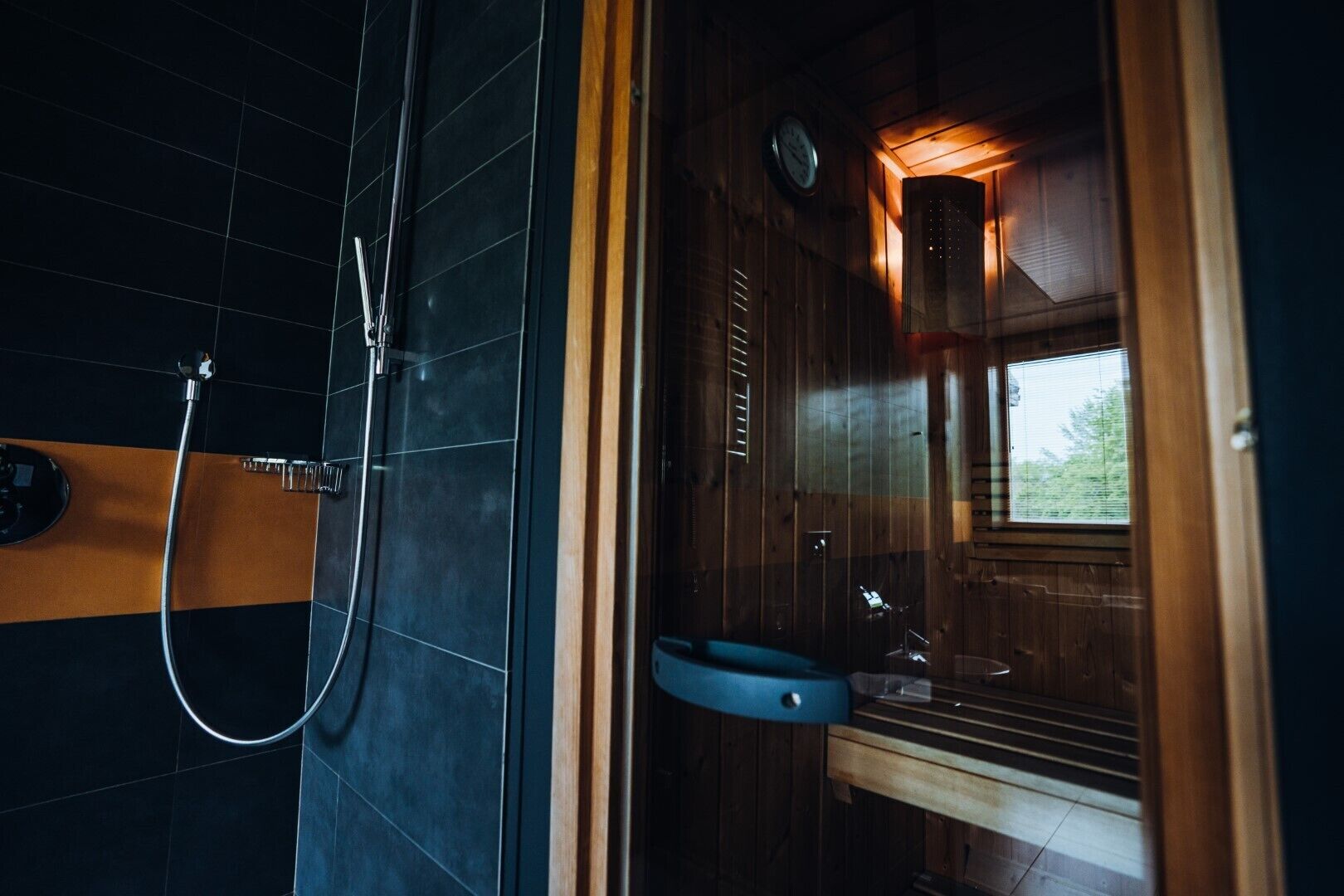 A wooden cabin-style bathroom with a shower, a sink, and a window.