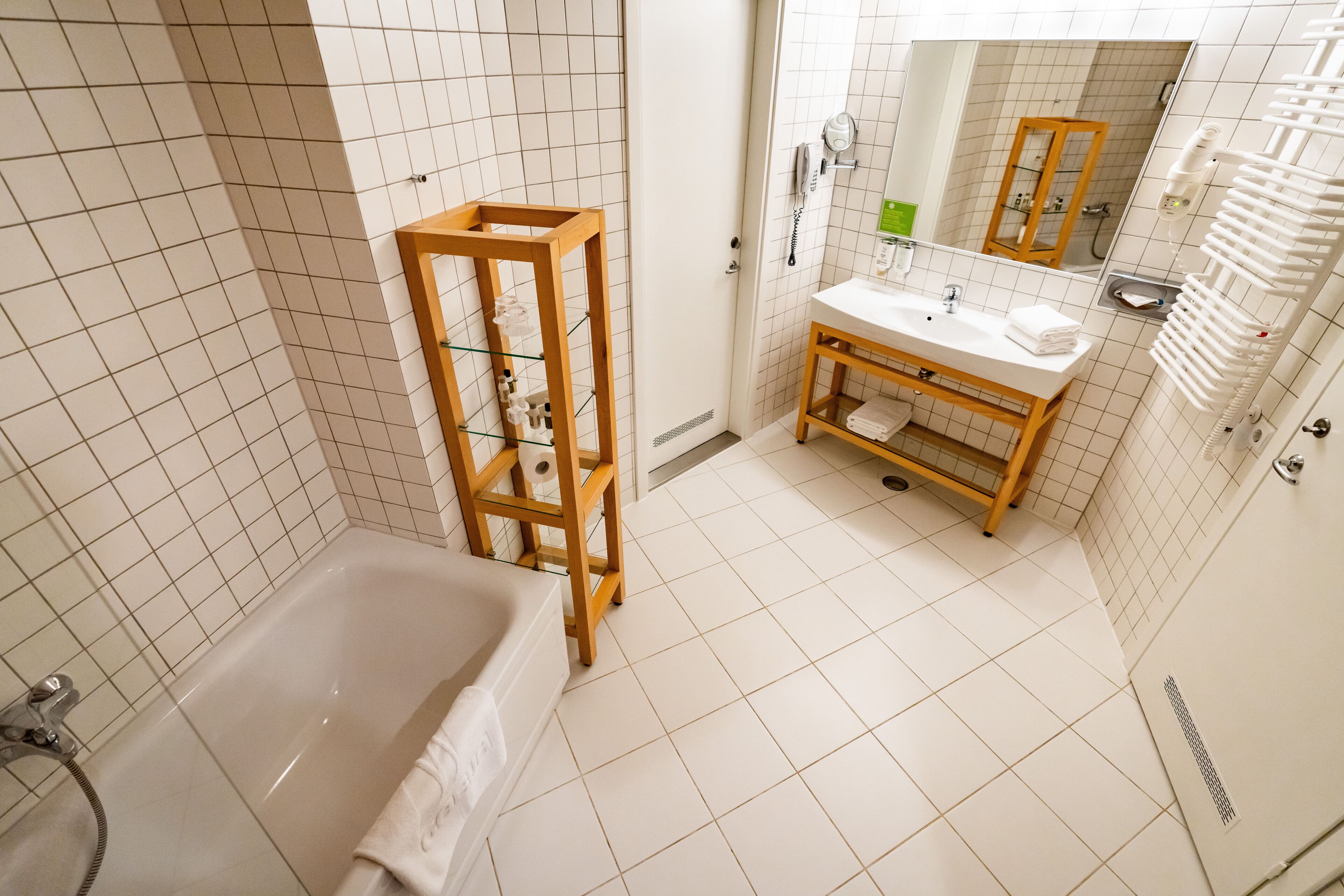 A modern bathroom with a bathtub, wooden vanity, and a mirror.