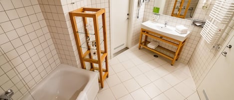 A modern bathroom with a bathtub, wooden vanity, and a mirror.