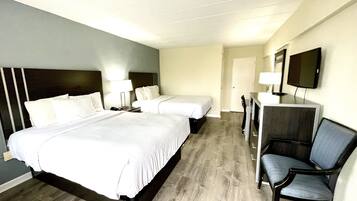 A hotel room with two beds, a desk with a chair, a television, and a door.