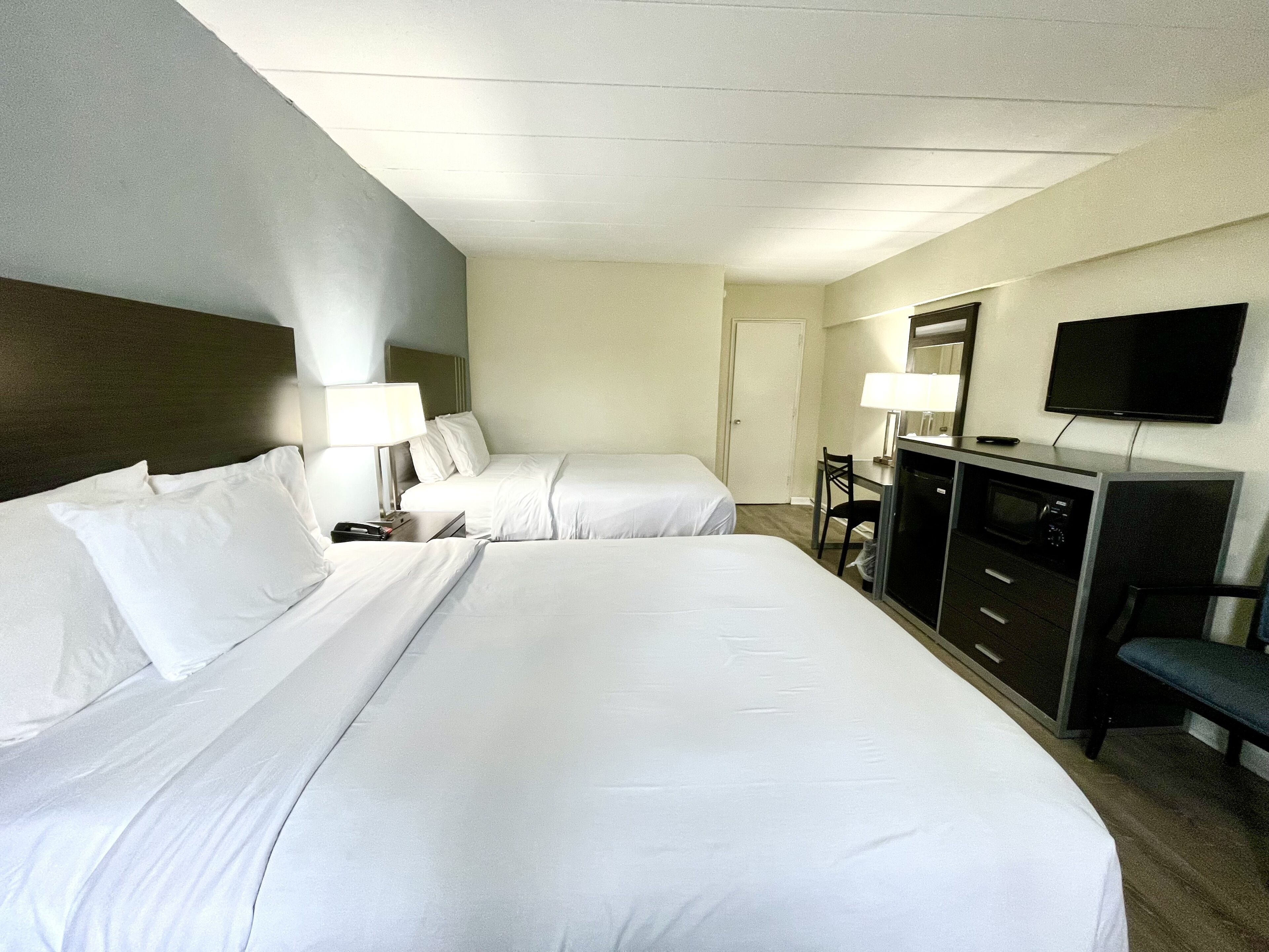 Een hotelkamer met twee bedden, een bureau met stoel, een televisie en een minibar.