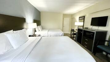 Een hotelkamer met twee bedden, een bureau met stoel, een televisie en een minibar.