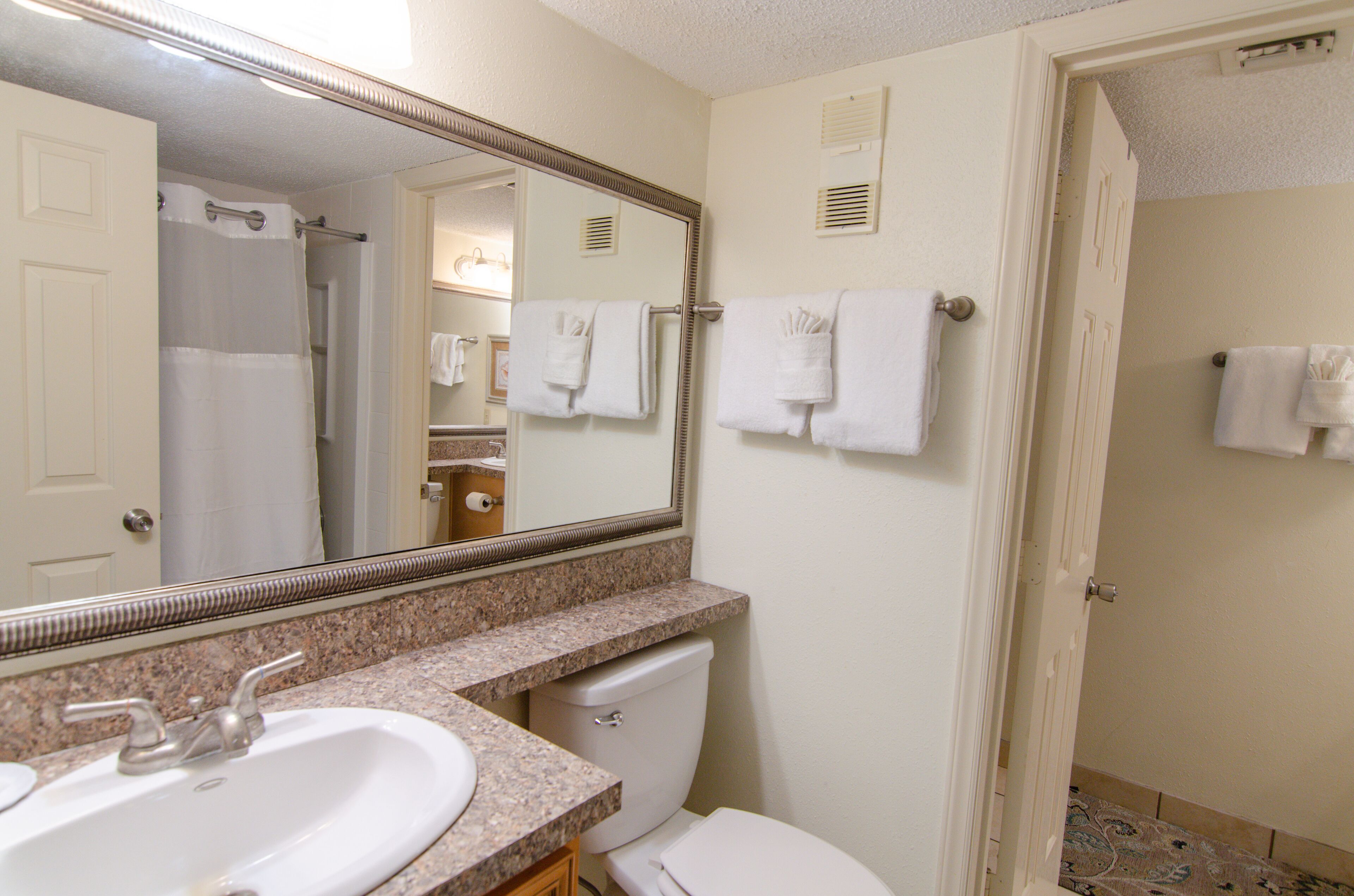 Une salle de bain d’hôtel avec un lavabo, des toilettes et un grand miroir.