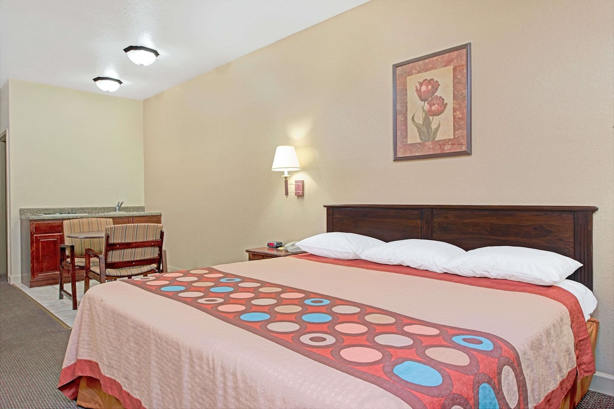Habitación de hotel con una cama grande, una mesita de noche, una silla, un escritorio y un baño.