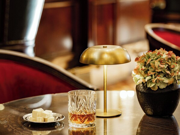 A table with a glass, a small dish of butter, a gold lamp, and a vase with flowers. - Grecotel Larissa Imperial (Larissa)