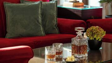 A red sofa with green cushions, a glass table with a decanter, glasses, and cubes of butter.
