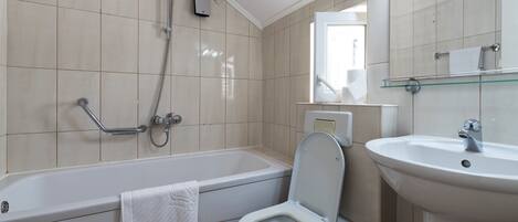 Un baño con bañera, inodoro y lavamanos.