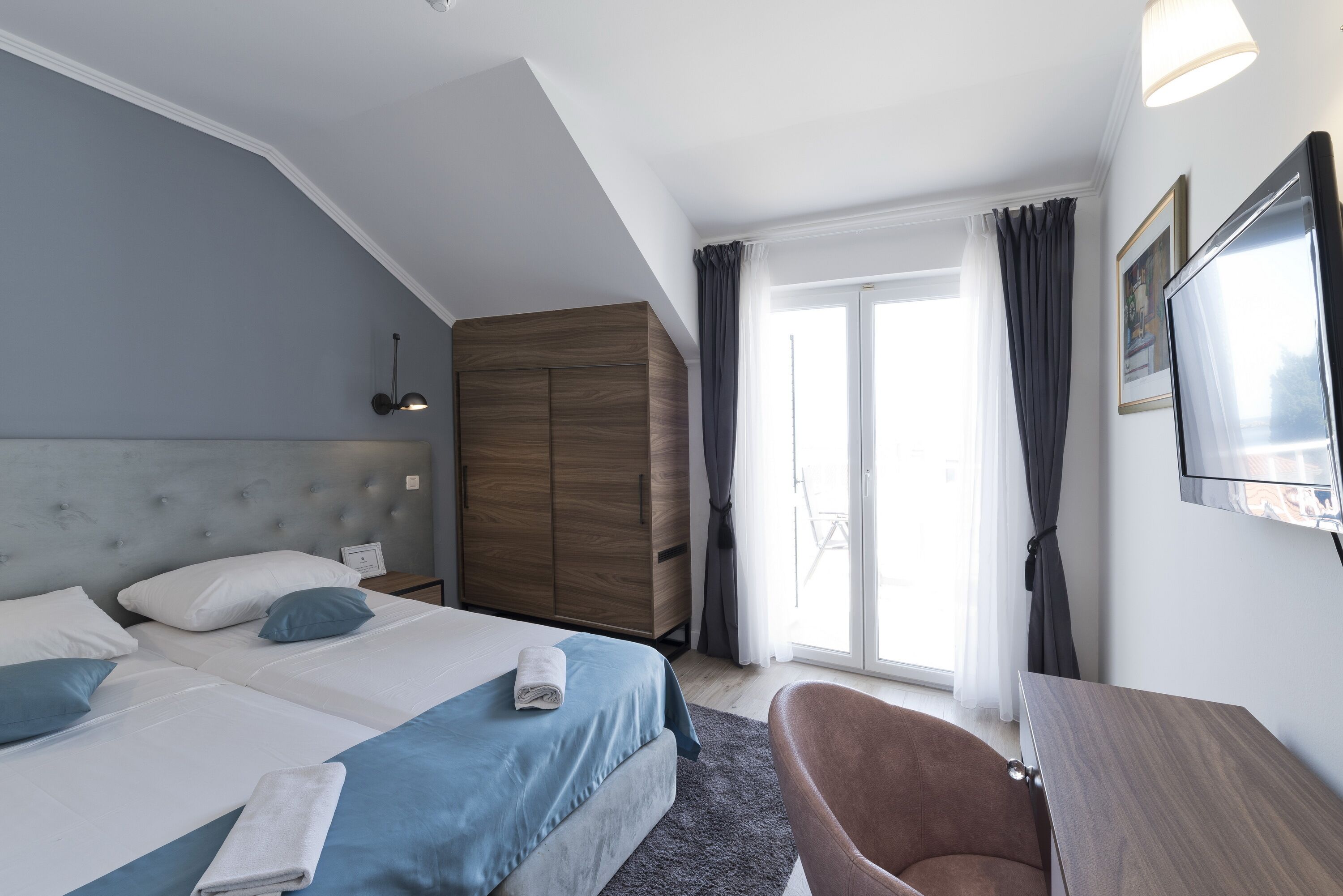 Una habitación de hotel moderna con una cama grande, un armario, un escritorio y una silla.