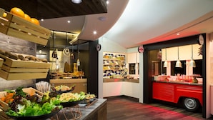 Une cuisine moderne avec des étagères en bois, un comptoir rouge de style rétro et divers produits alimentaires exposés.