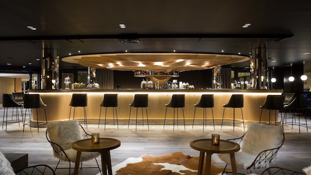 Un espace bar doté d’un comptoir circulaire, de plusieurs tabourets et d’un tapis en peau de vache.