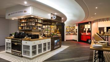 A bakery with a display of breads and pastries, a coffee machine, and a clock on the wall.