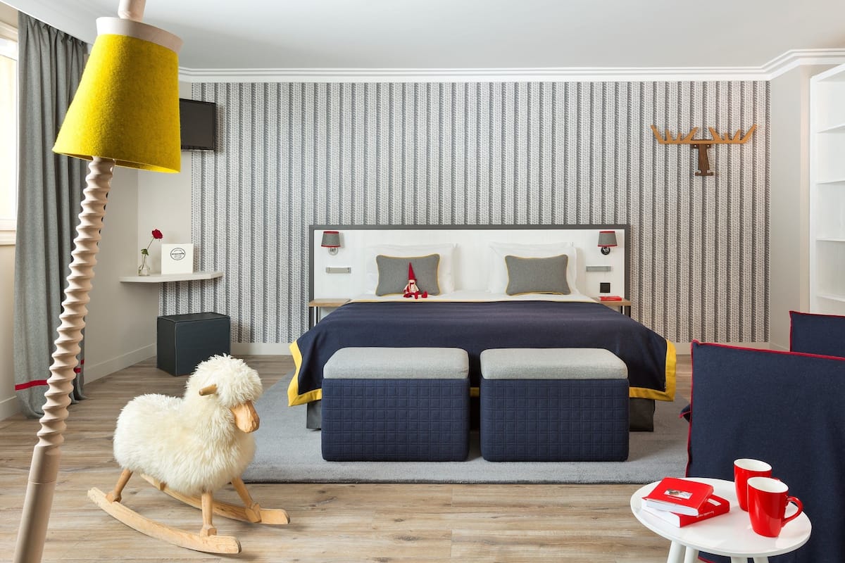 Une chambre à coucher avec un lit, une table de chevet, une lampe et un mouton à bascule.