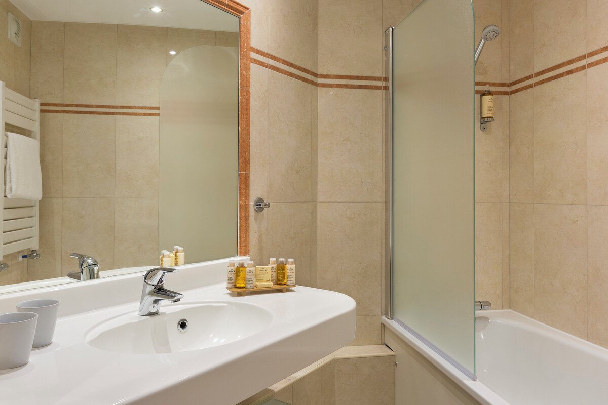 Un baño con un espejo grande, un lavabo y una ducha.