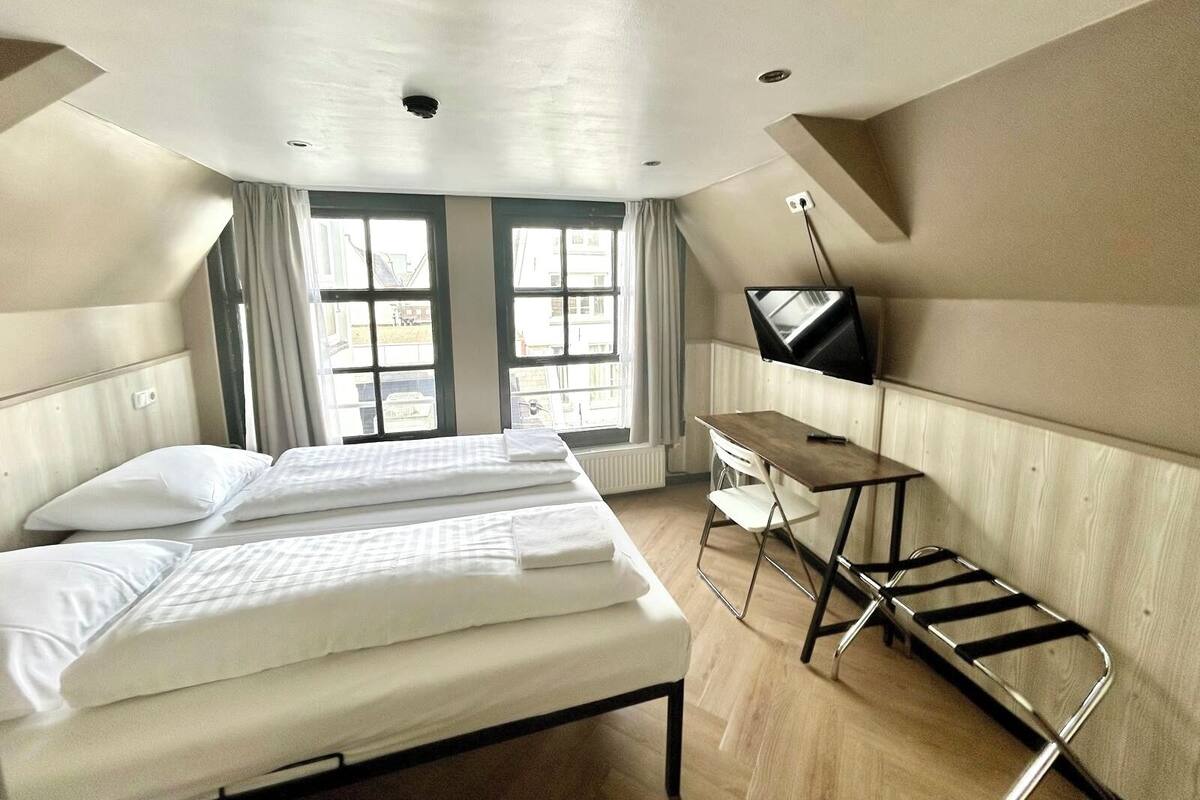 Ein Hotelzimmer mit einem Bett, einem Schreibtisch, einem Fernseher und großen Fenstern.