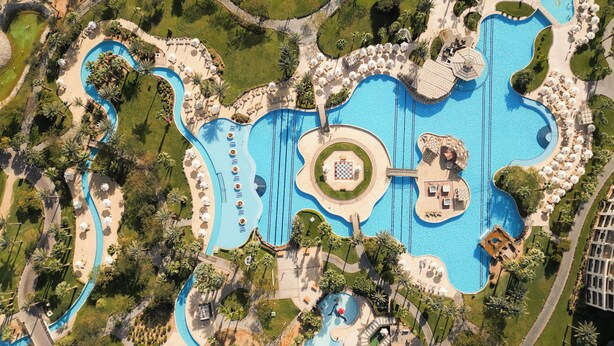 An aerial view of a resort with multiple swimming pools, sun loungers, and palm trees. - Steigenberger ALDAU Beach Hotel (Hurghada)