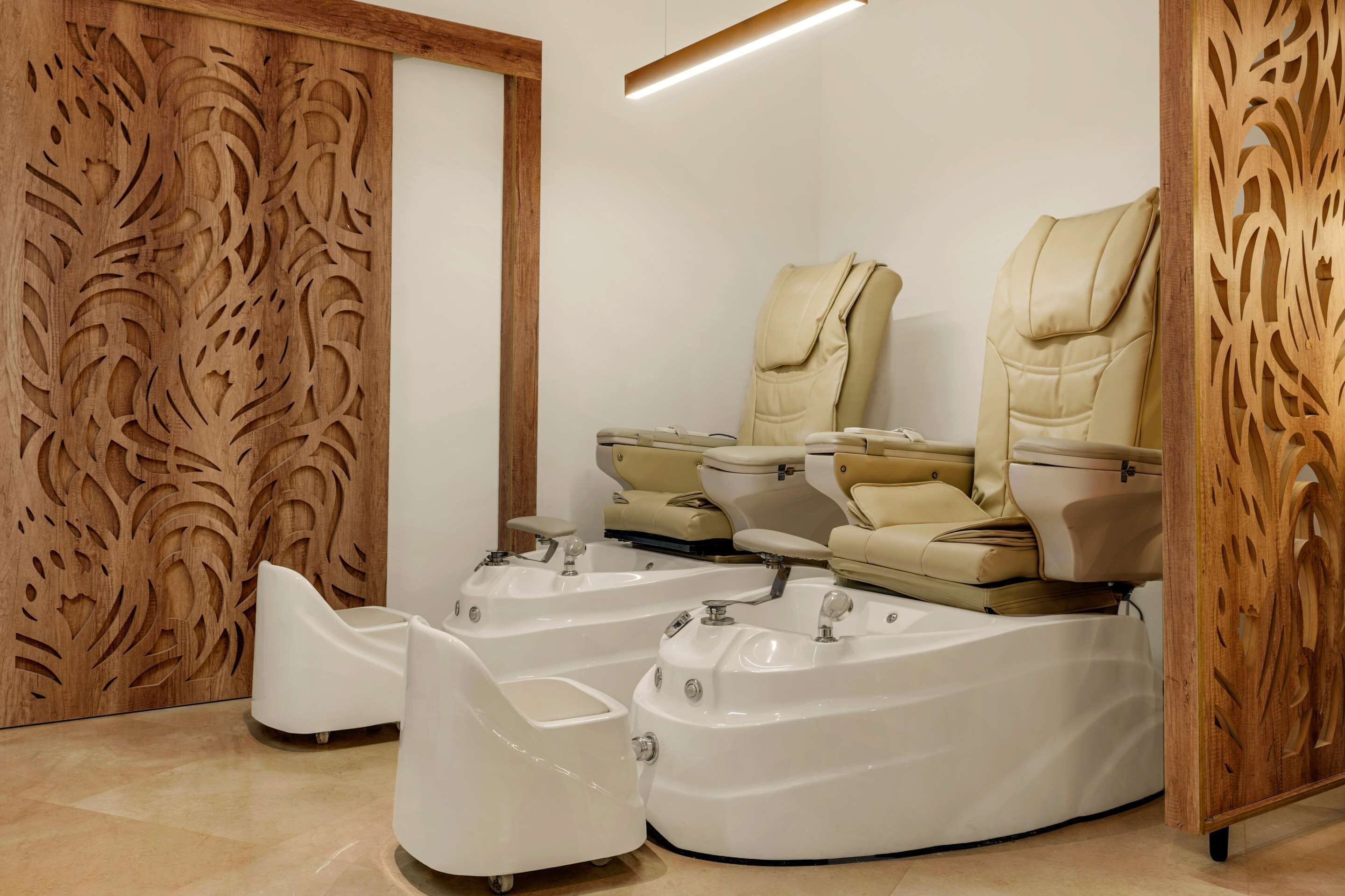 A modern spa room with three massage chairs, a wooden decorative panel, and a white sink.