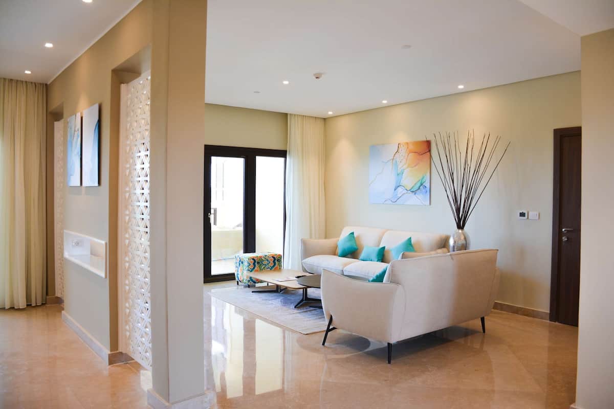 Un salon moderne avec un canapé blanc, des coussins turquoise et un vase décoré de branches.