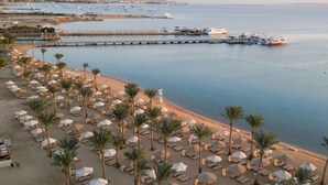 A beachside resort with rows of sun loungers and umbrellas, a pier with boats, and a calm sea. - Steigenberger ALDAU Beach Hotel (Hurghada)